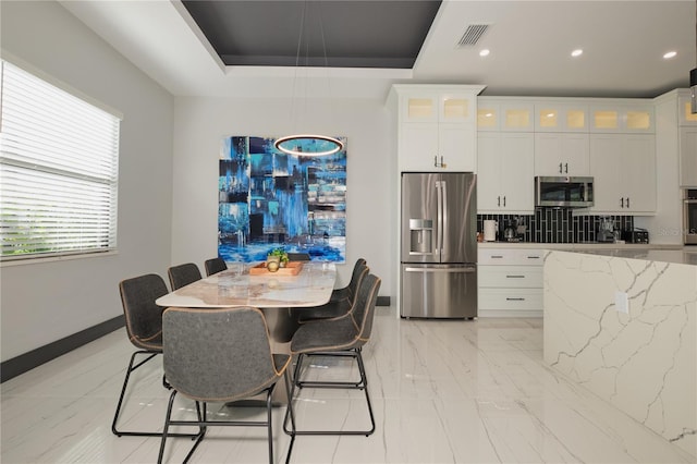 kitchen with white cabinets, light stone counters, stainless steel appliances, a raised ceiling, and tasteful backsplash