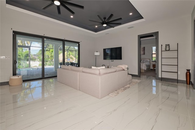 living room with a tray ceiling and ceiling fan