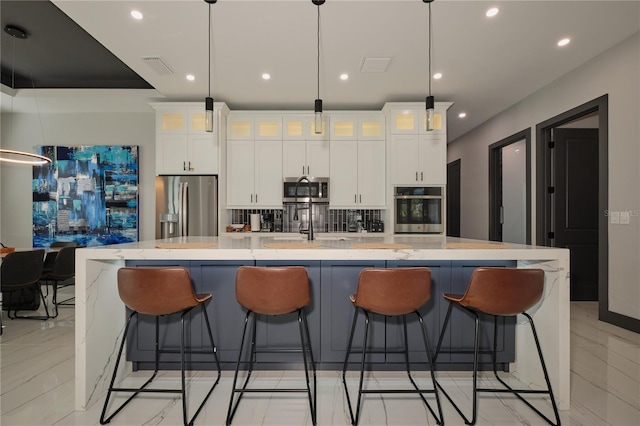 kitchen featuring a large island with sink, decorative light fixtures, and stainless steel appliances