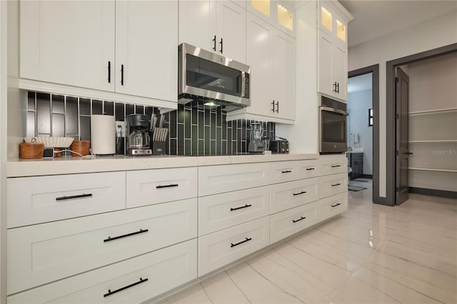 kitchen with appliances with stainless steel finishes, white cabinetry, and decorative backsplash