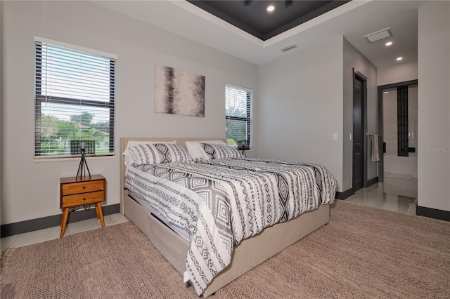 bedroom with a tray ceiling and light tile patterned floors