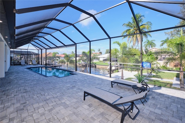 view of swimming pool featuring a water view, a patio area, and glass enclosure