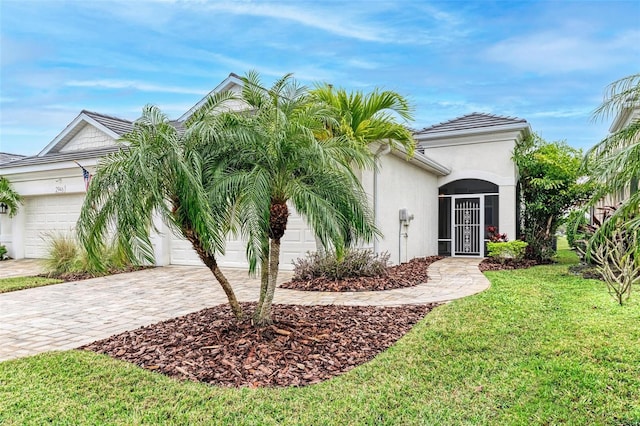 view of front of property featuring a front lawn, decorative driveway, an attached garage, and stucco siding