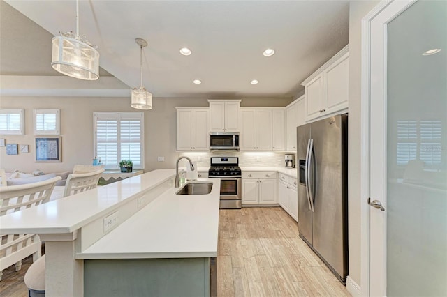 kitchen with stainless steel appliances, light countertops, backsplash, light wood-style floors, and a sink