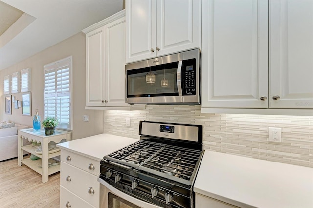 kitchen with tasteful backsplash, white cabinets, light wood-style flooring, appliances with stainless steel finishes, and light countertops