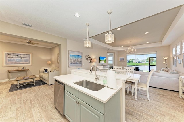 kitchen with open floor plan, a raised ceiling, a sink, and dishwasher