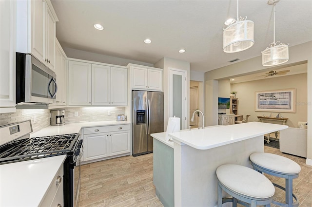 kitchen featuring white cabinetry, appliances with stainless steel finishes, decorative backsplash, and a breakfast bar area