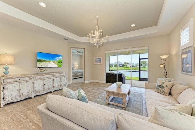 living room featuring plenty of natural light, baseboards, a raised ceiling, and wood finished floors