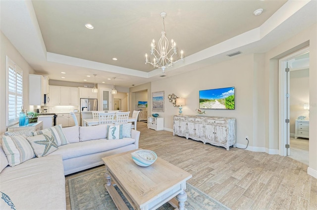 living area featuring light wood finished floors, baseboards, a raised ceiling, and recessed lighting