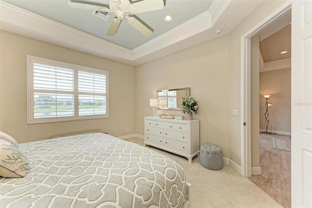 bedroom featuring visible vents, a tray ceiling, baseboards, and ornamental molding