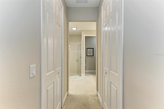 hallway featuring light carpet and baseboards