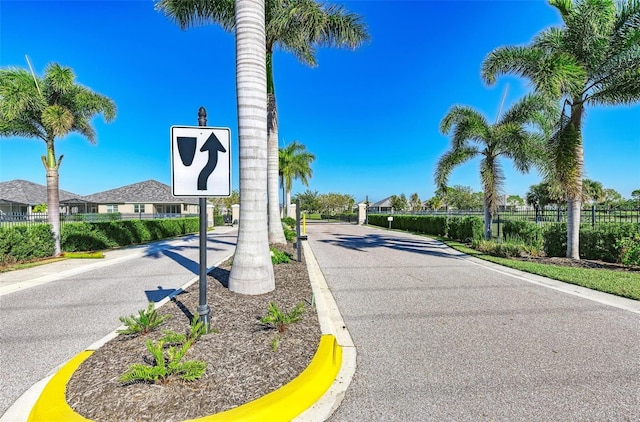 view of street with curbs, a gated entry, and a residential view