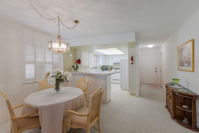 dining space featuring light colored carpet, an inviting chandelier, and a textured ceiling