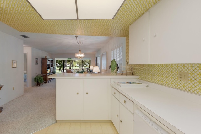 kitchen featuring dishwasher, a chandelier, white cabinetry, kitchen peninsula, and pendant lighting