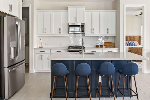 kitchen featuring white cabinetry, an island with sink, a kitchen bar, and stainless steel appliances