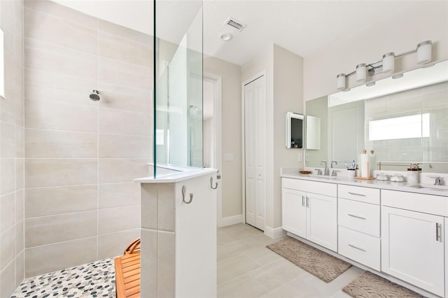 bathroom with tiled shower, vanity, and tile patterned flooring