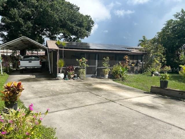 view of front of property with solar panels, a carport, and a front lawn