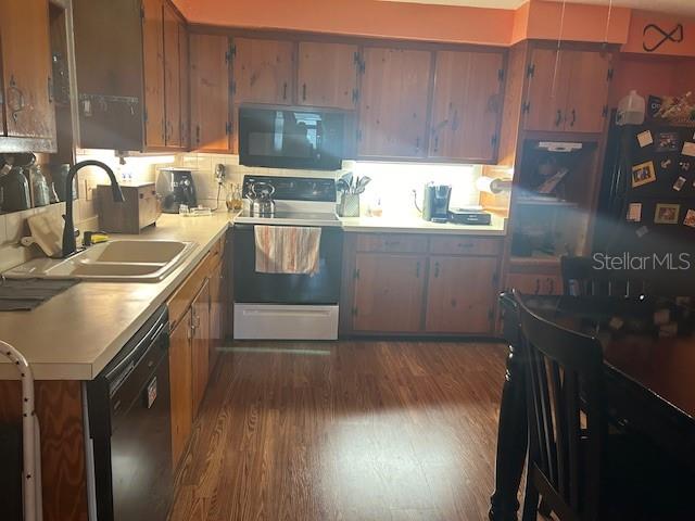 kitchen featuring black appliances, dark hardwood / wood-style flooring, and sink