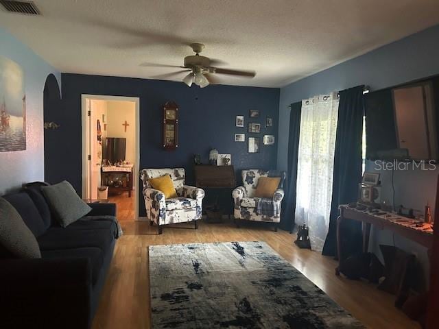 living room featuring a textured ceiling, ceiling fan, and wood-type flooring