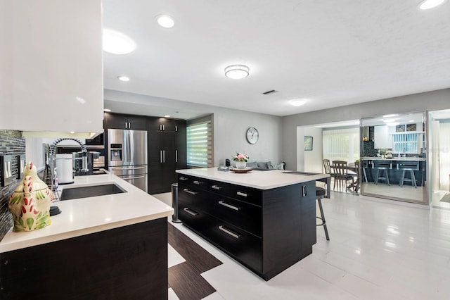 kitchen featuring a breakfast bar area, stainless steel fridge with ice dispenser, and sink