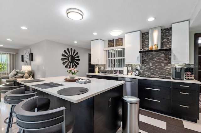 kitchen featuring wall chimney exhaust hood, stainless steel dishwasher, a center island, sink, and decorative backsplash