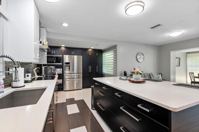 kitchen with stainless steel fridge, tasteful backsplash, a center island, sink, and black electric cooktop