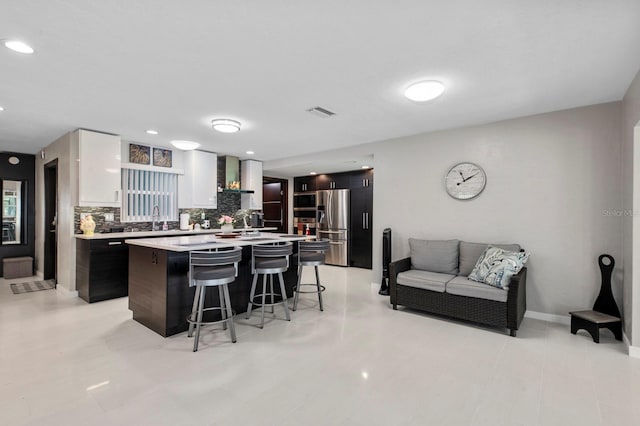 kitchen featuring white cabinets, backsplash, a kitchen bar, a kitchen island, and stainless steel fridge with ice dispenser