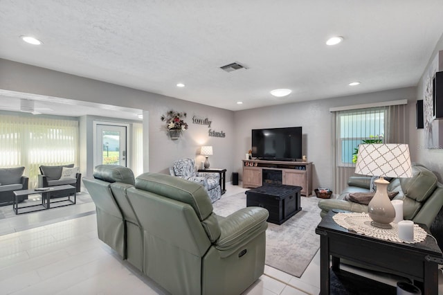 living room with a textured ceiling, a healthy amount of sunlight, and light tile patterned floors