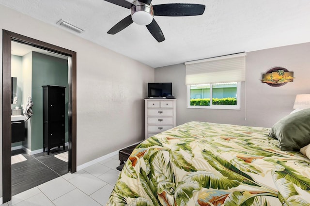 bedroom with ceiling fan, light tile patterned floors, a textured ceiling, and ensuite bath