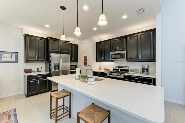 kitchen with a kitchen breakfast bar, stainless steel appliances, a textured ceiling, and sink