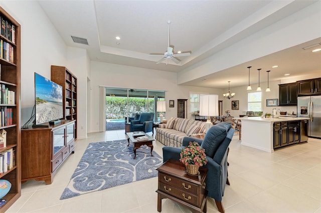 living room featuring visible vents, recessed lighting, ceiling fan with notable chandelier, and a raised ceiling