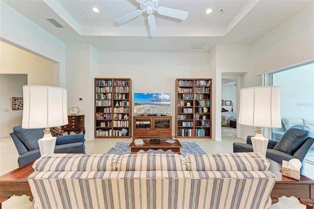 tiled living room with a tray ceiling and ceiling fan