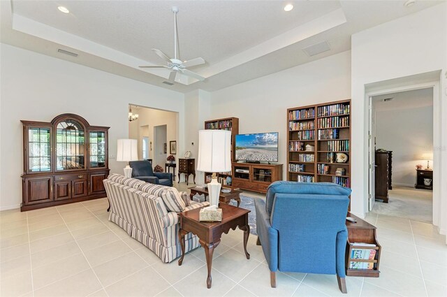 living room with a raised ceiling, light tile patterned floors, and ceiling fan