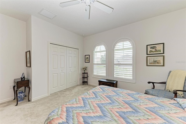 bedroom featuring a closet, ceiling fan, light carpet, and a textured ceiling