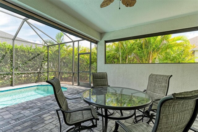 exterior space featuring glass enclosure, outdoor dining space, a ceiling fan, and an outdoor pool