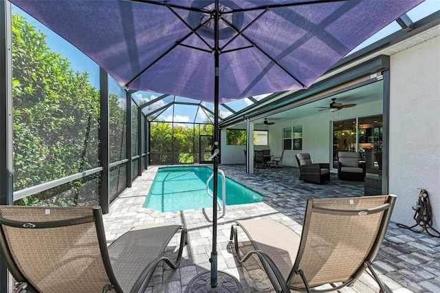 view of pool featuring an outdoor hangout area, glass enclosure, a patio area, and ceiling fan