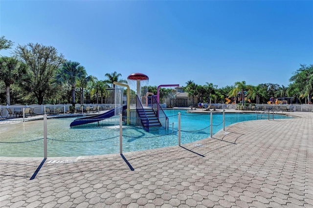 community pool featuring a water play area, playground community, and fence