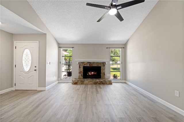 3240 Flamingo Ln, Mulberry, FL 33860 - unfurnished living room featuring a textured ceiling, a stone fireplace, wood finished floors, and ceiling fan