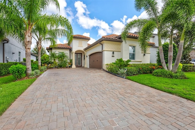 mediterranean / spanish home featuring a front yard and a garage