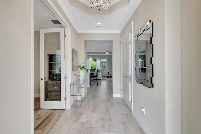 hallway featuring light wood-type flooring, a notable chandelier, and ornamental molding