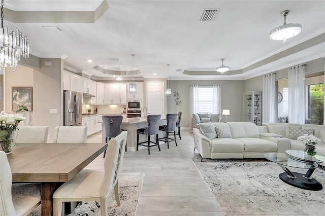 interior space with ceiling fan, ornamental molding, light wood-type flooring, and a tray ceiling