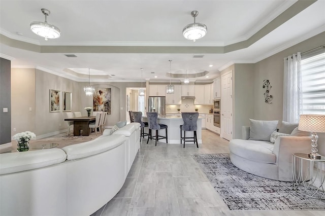 living room featuring a raised ceiling and ornamental molding