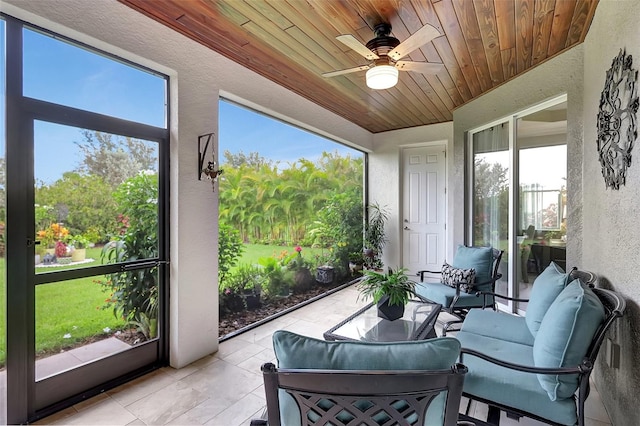 sunroom / solarium featuring a healthy amount of sunlight, ceiling fan, and wooden ceiling