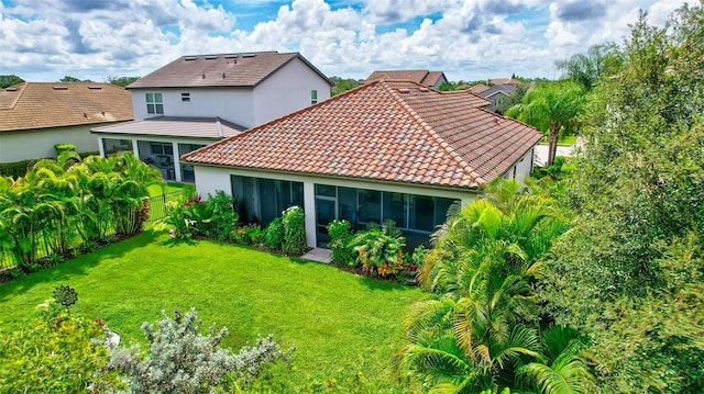 back of property featuring a sunroom and a lawn