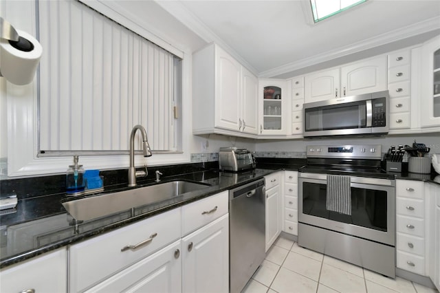 kitchen with ornamental molding, light tile patterned floors, appliances with stainless steel finishes, and white cabinets