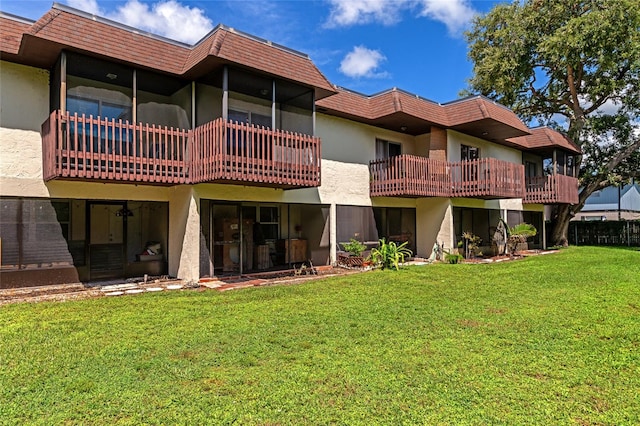 back of property featuring a balcony and a yard