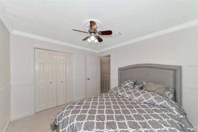 carpeted bedroom with ceiling fan, ornamental molding, and a closet