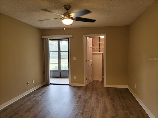 unfurnished room with a textured ceiling, ceiling fan, and dark wood-type flooring