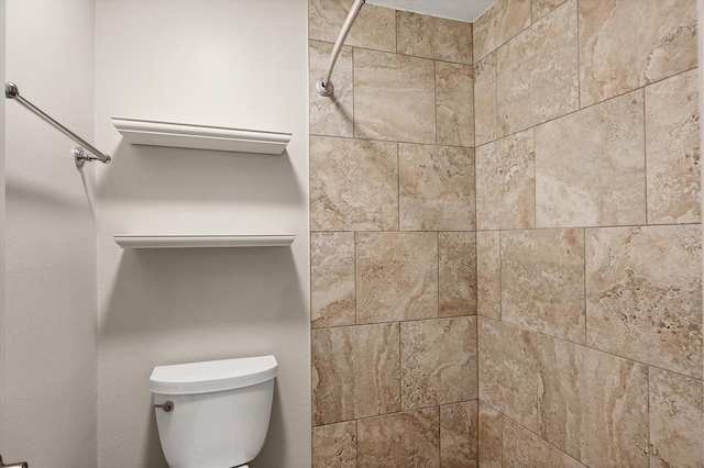 bathroom with a tile shower and toilet