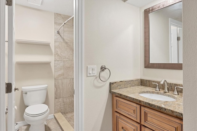 bathroom with a tile shower, vanity, tile patterned flooring, and toilet